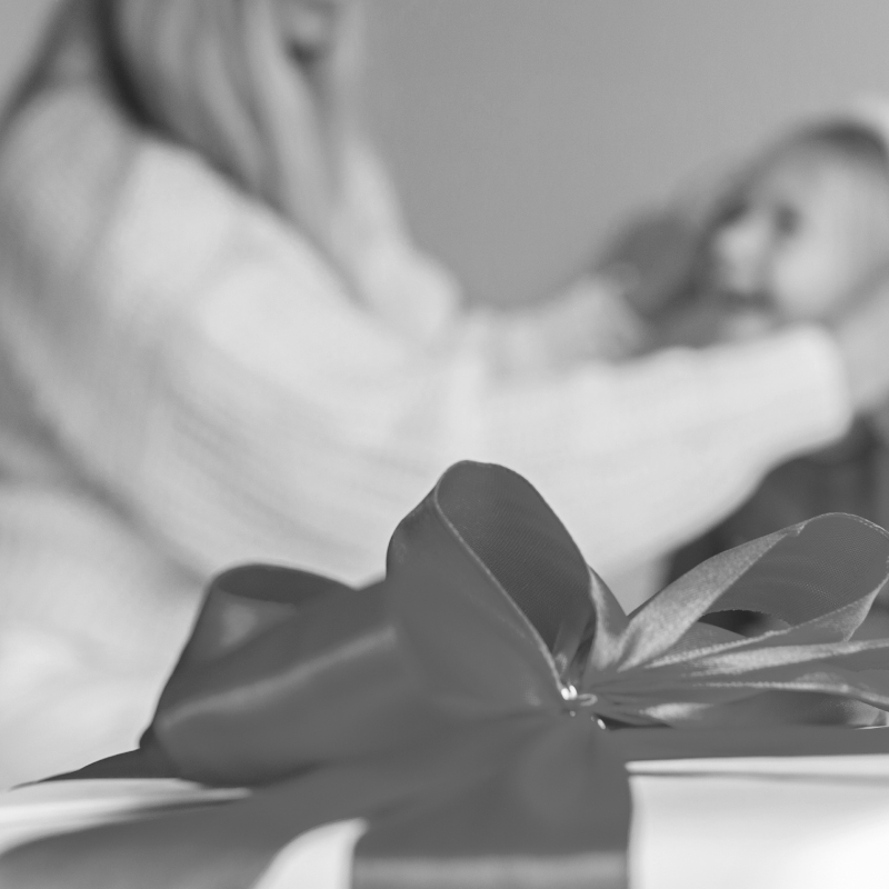 B&W image of a mother putting a santa hat on her daughter's head