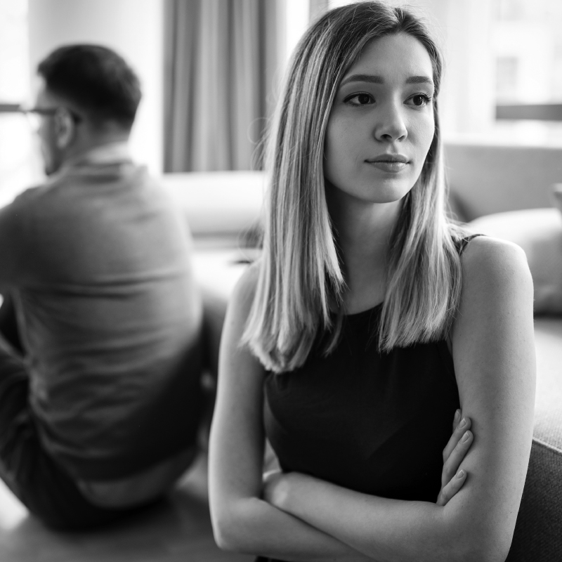 B&W Image of a man and women sitting on a bed with the women facing away in anger